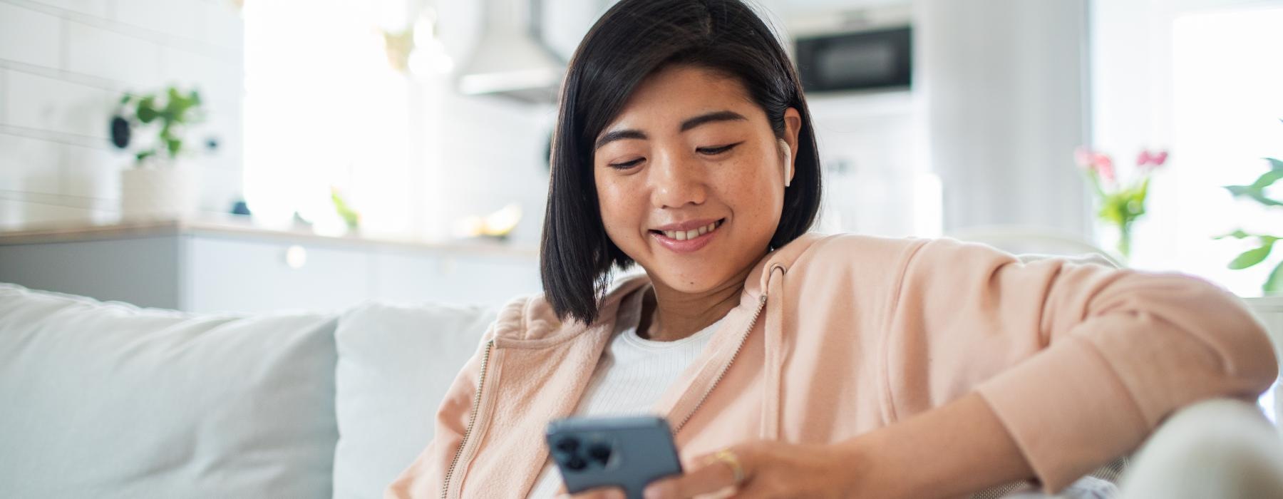 a woman sitting on a couch and looking at a phone