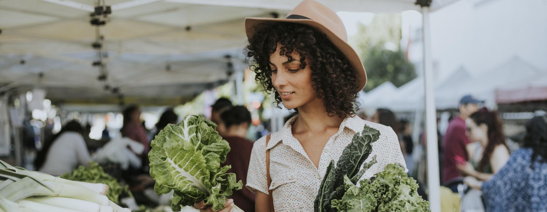 a woman holding a bunch of vegetables